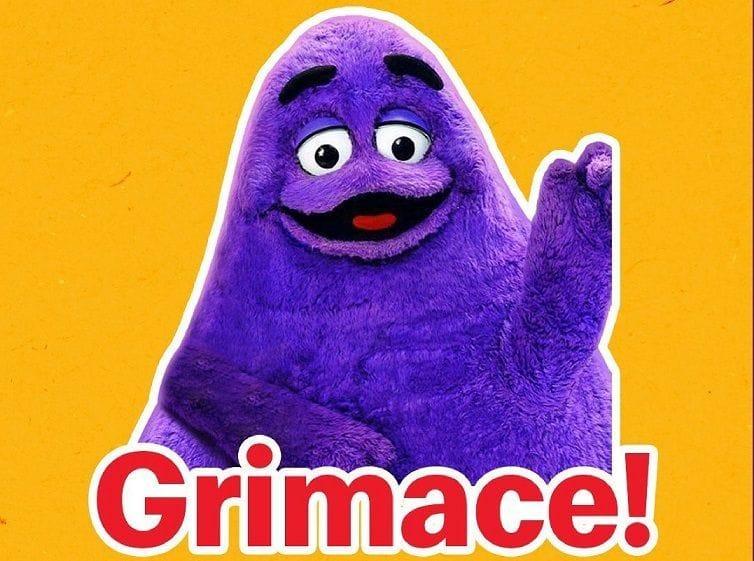 grimace, a mcdonalds mascot character that is a purple blob. it has something like a beak or snout and is attempting to smile cheerfully.
red text with white outline says "Grimace!"
